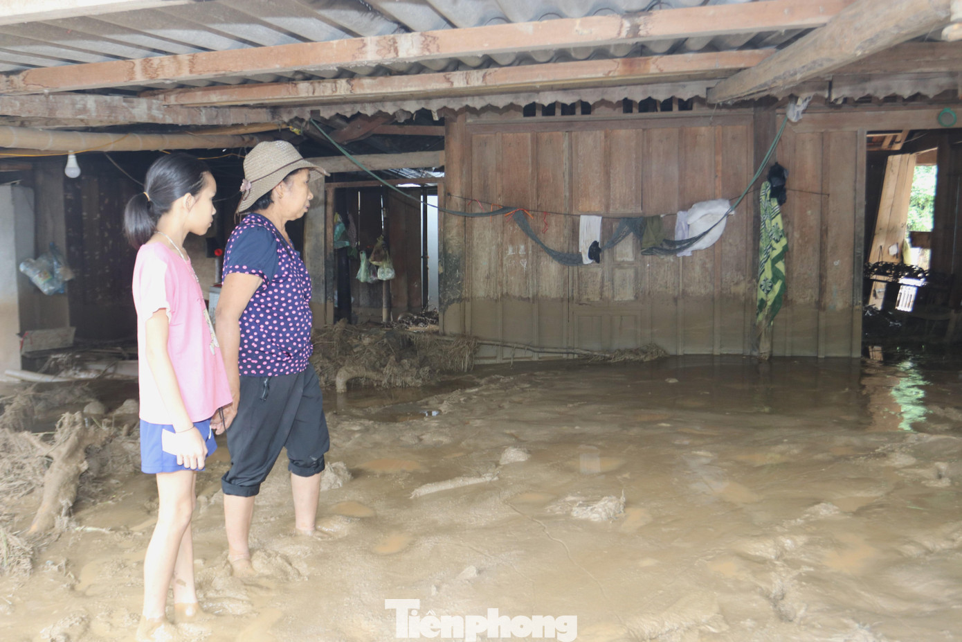 Bà Ngân cùng cháu gái trước căn nhà bị lũ quét tàn phá. Mọi vật dụng trong nhà đã hư hỏng hoàn toàn.