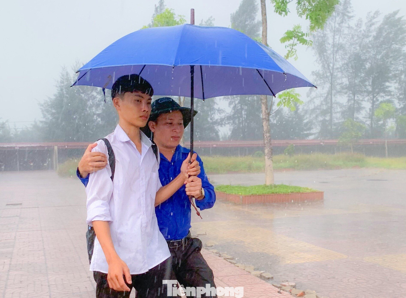 Các đoàn viên thanh niên tình nguyện đã chia nhau mang theo ô ra tận đường để đón các thí sinh không có ô, áo mưa vào trường.