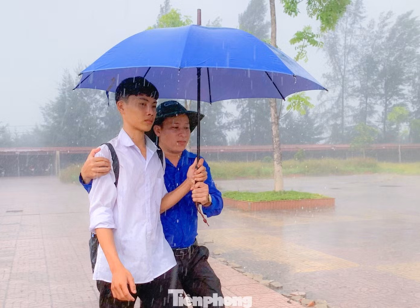 Các đoàn viên thanh niên tình nguyện đã chia nhau mang theo ô ra tận đường để đón các thí sinh không có ô, áo mưa vào trường.