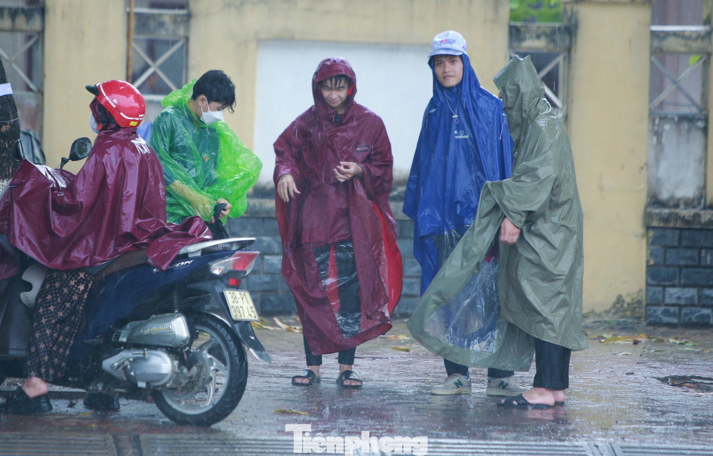 Nhiều phụ huynh đứng ngoài cổng trường chờ con em thi trong cơn mưa tầm tã.