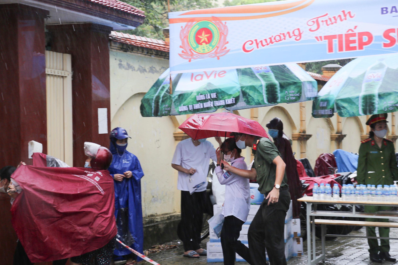 Đại úy Nguyễn Sỹ Nguyên - Phó Bí thư Đoàn Công an tỉnh Nghệ An dùng ô của mình che cho thí sinh.