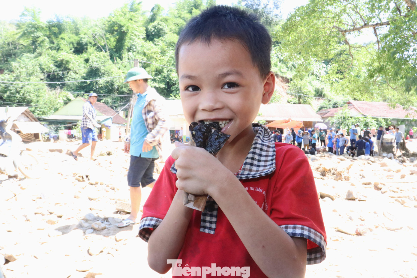 Cậu bé người Khơ Mú ngấu nghiến chiếc bánh gai từ đoàn từ thiện. Em hồn nhiên với bữa trưa của mình.