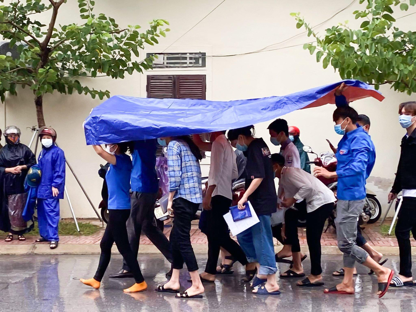 Ảnh hưởng của áp thấp nhiệt đới, ngày đầu tiên diễn ra kỳ thi tốt nghiệp THPT năm 2021, địa bàn Nghệ An có mưa nên từ sáng sớm, đoàn viên thanh niên tình nguyện đã chuẩn bị ô che mưa, đón đưa các sĩ tử vào phòng thi không bị ướt.