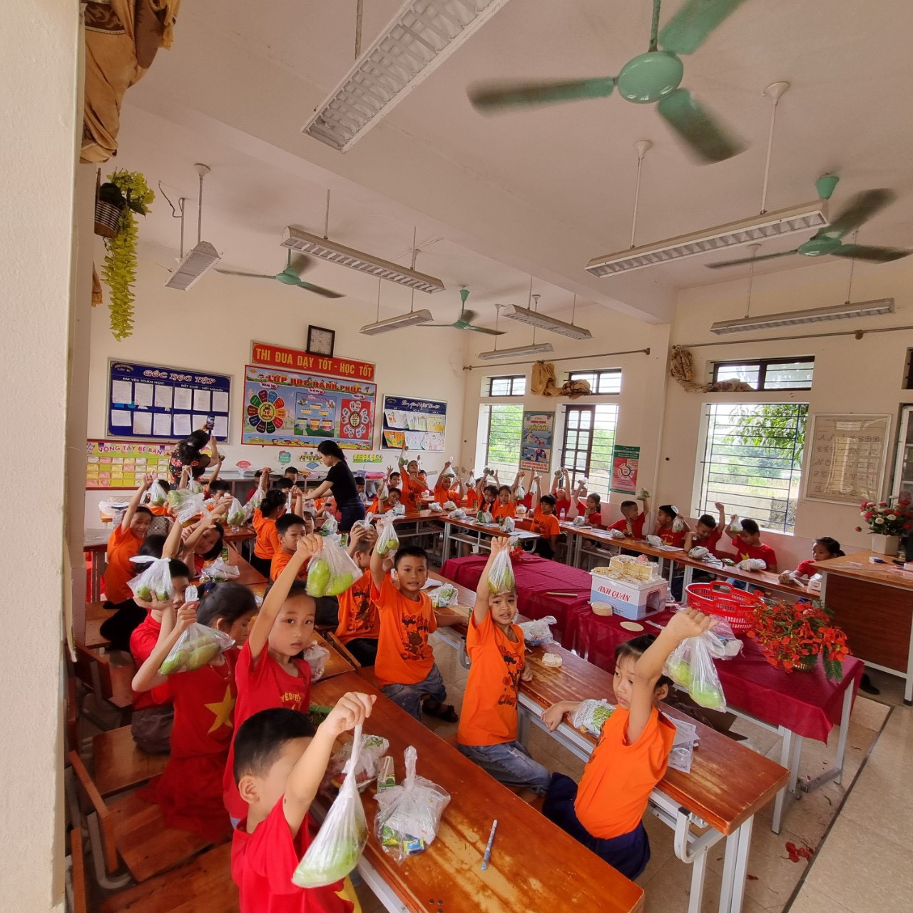 Mỗi em học sinh được tặng túi đựng 2 quả xoài. Ai cũng phấn khởi, thích thú.