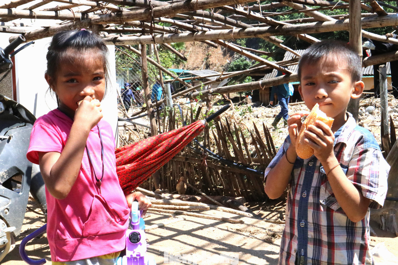 Vừa nhận chiếc bánh mì từ bà nội, hai chị em Lô Thị Huyền (học sinh lớp 2, trường TH Tà Cạ) chia đôi để ăn trưa. Huyền không tranh giành mà nhường cho em trai phần nhiều hơn. Ngôi nhà đã bị lũ tàn phá, bố mẹ nghèo khó gắng gượng bới bùn bòn mót tài sản còn sót lại. Chị em Huyền ngây thơ lang thang chơi bên bờ suối Huồi Giảng.
