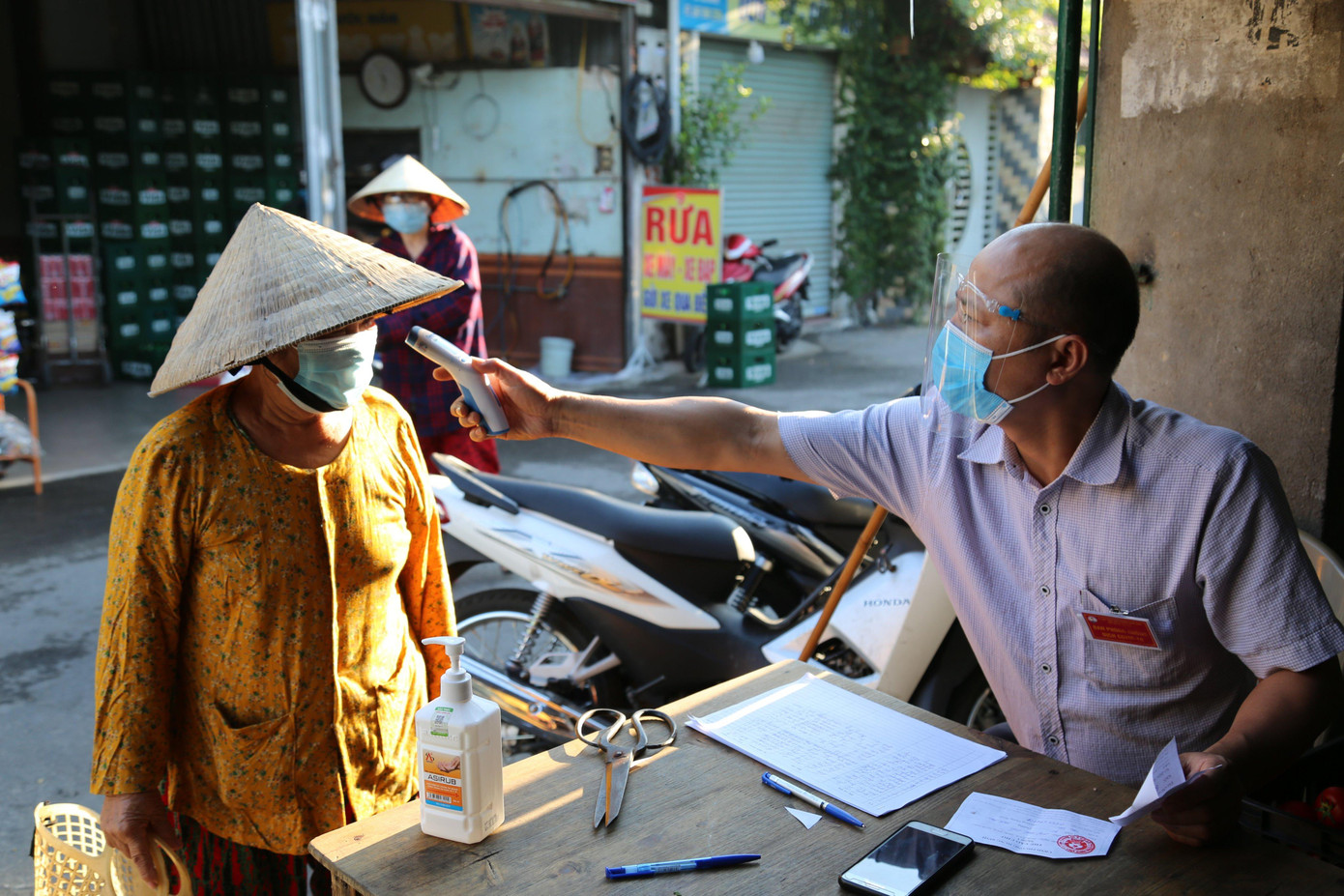 Người dân khi đến chợ sẽ được đo thân nhiệt, thực hiện các thủ tục cần thiết trong công tác phòng, chống dịch COVID-19.