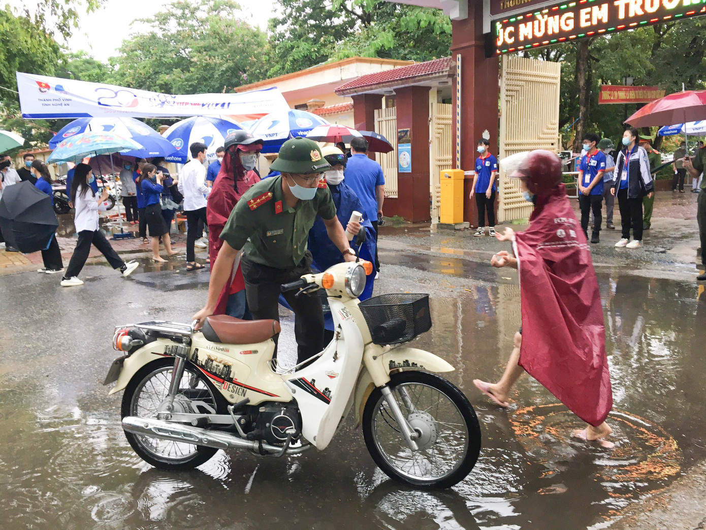 Đoàn viên Đoàn Công an tỉnh Nghệ An hỗ trợ thí sinh đến muộn dắt xe vào bãi để các em kịp vào phòng thi.