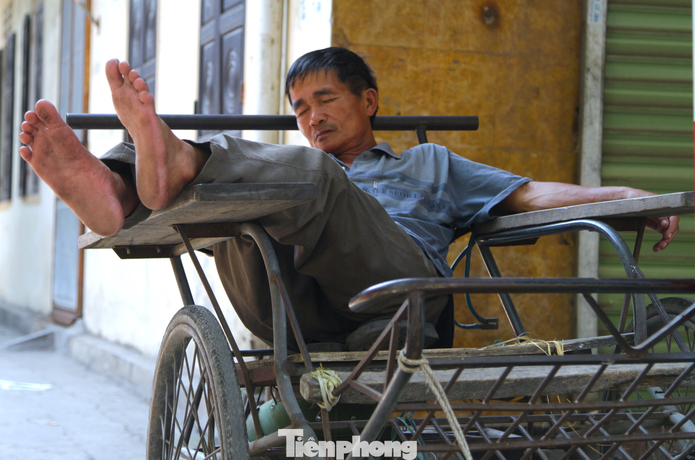 Nằm chờ người thuê chở hàng, người đàn ông này tranh thủ chợp mắt ngay trên chiếc xe xích lô của mình.
