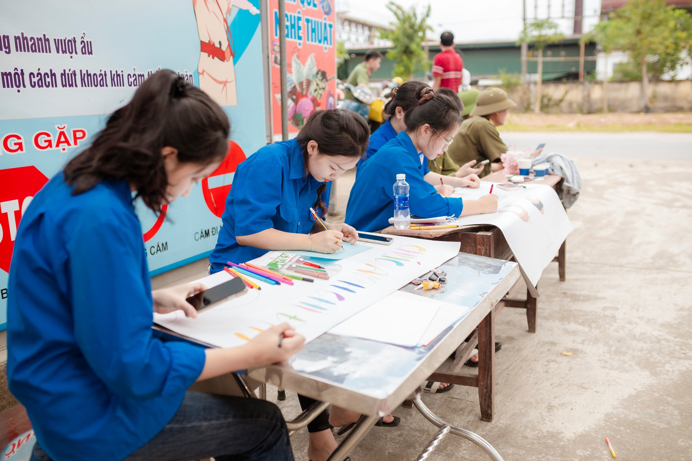 Trước cổng trường THPT Anh Sơn 3, tranh thủ chưa đến giờ thi, những nữ tình nguyện viên thể hiện tài vẽ tranh với những câu cổ động đầy màu sắc.
