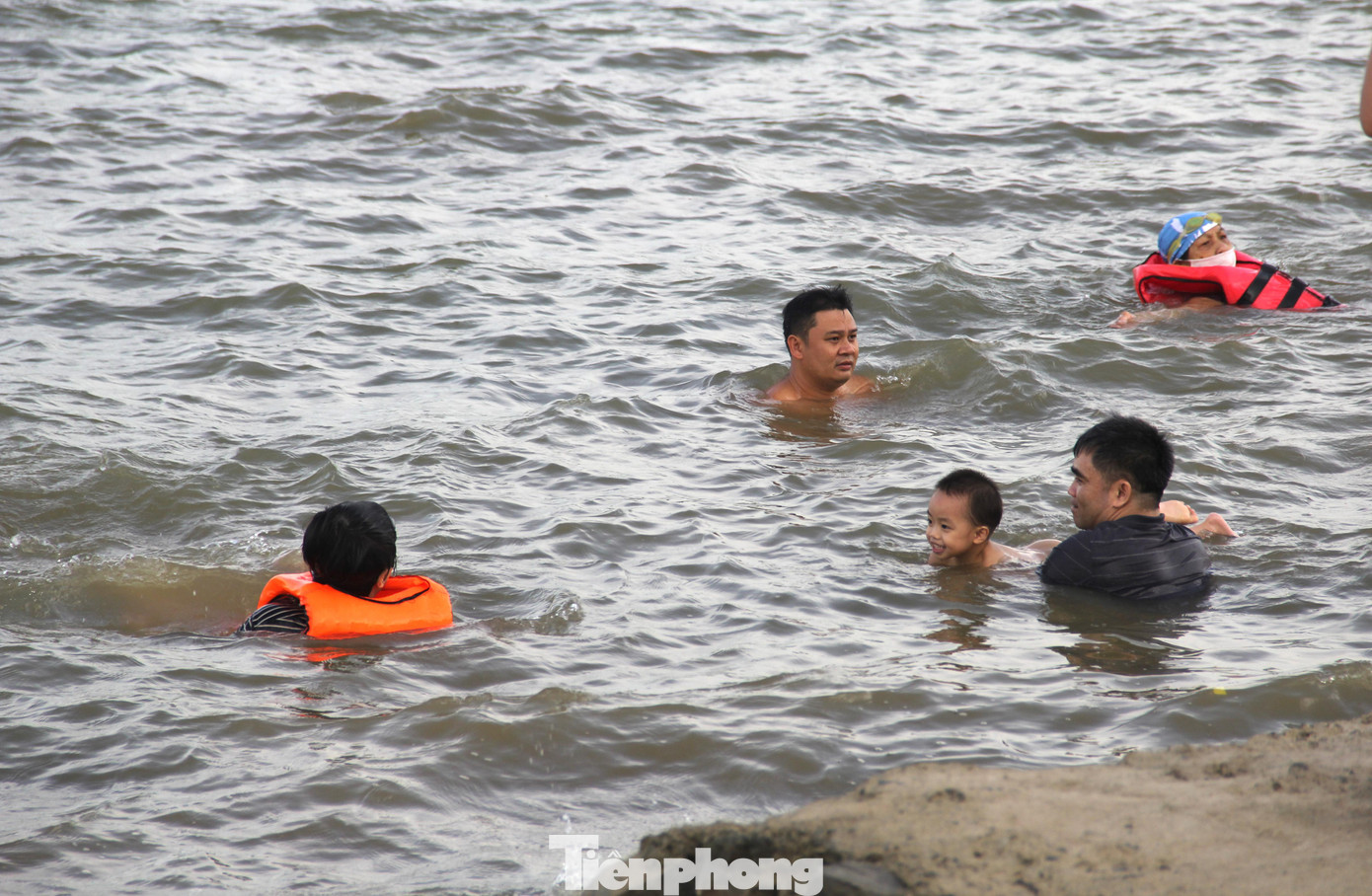 Nhiều người đưa con nhỏ ra tắm, cho con tập bơi ở gần bờ.
