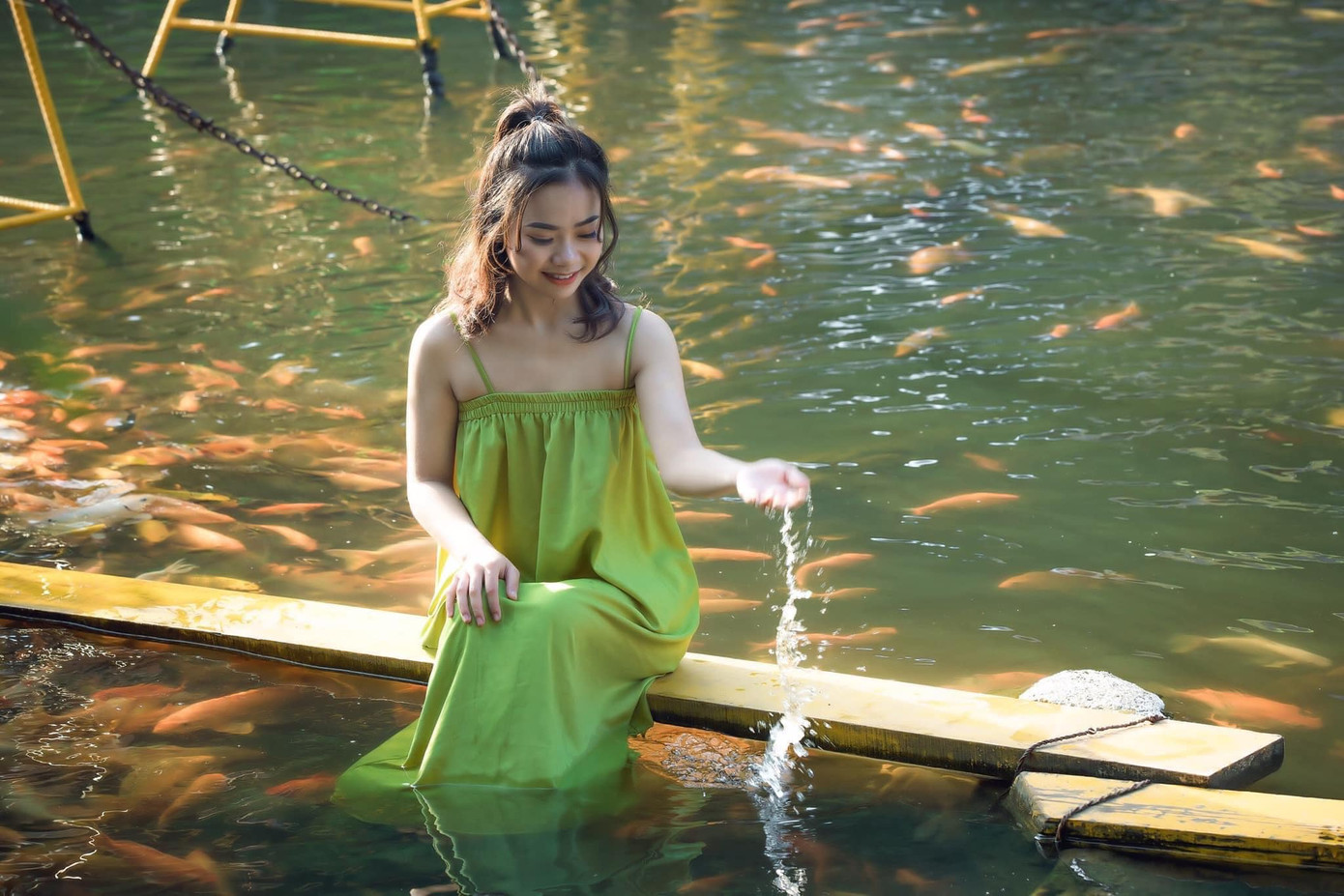 Nhiều thiếu nữ lưu giữ những khoảnh khắc đáng nhớ bên dòng suối cá vàng trong mát.