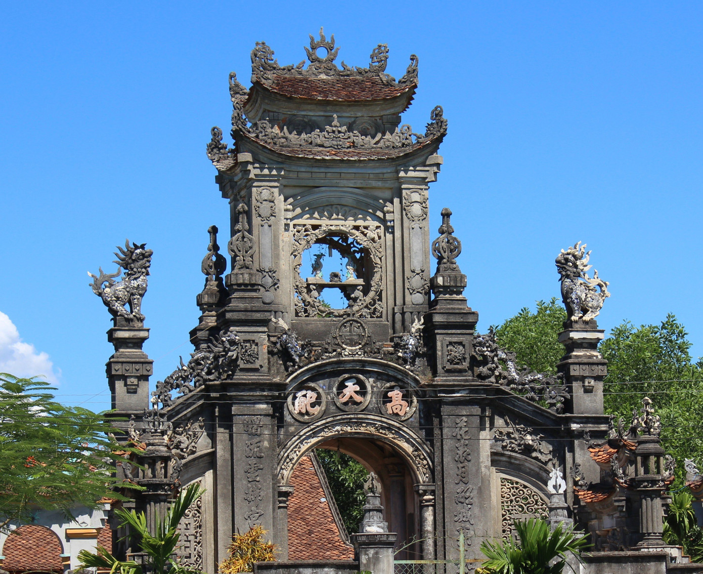 Cổng tam quan có 3 tầng, cao hơn 10m (cao nhất di tích). Tầng 1 rộng 15 m2, được tạo nên bởi 4 cột trụ lớn. Thân và đỉnh trụ được giật cấp và trang trí các họa tiết. Các trụ được nối với nhau tạo nên 4 cửa thông ra 4 hướng. Trên cửa trước và cửa sau đều đắp tượng nghê chầu. Đặc biệt trên cửa trước có khắc 3 chữ Hán lớn với ý nghĩa chỉ sự cao lớn của công trình. Mái được đổ chụm lại thành hình vòm, có trang trí nhiều chi tiết, hoa văn đặc sắc. Cổng tam quan có 3 tầng, cao hơn 10m (cao nhất di tích). Tầng 1 rộng 15 m2, được tạo nên bởi 4 cột trụ lớn. Thân và đỉnh trụ được giật cấp và trang trí các họa tiết. Các trụ được nối với nhau tạo nên 4 cửa thông ra 4 hướng. Trên cửa trước và cửa sau đều đắp tượng nghê chầu. Đặc biệt trên cửa trước có khắc 3 chữ Hán lớn với ý nghĩa chỉ sự cao lớn của công trình. Mái được đổ chụm lại thành hình vòm, có trang trí nhiều chi tiết, hoa văn đặc sắc.