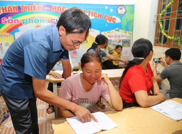 Thầy giáo tận tình dạy các chị, em học chữ.