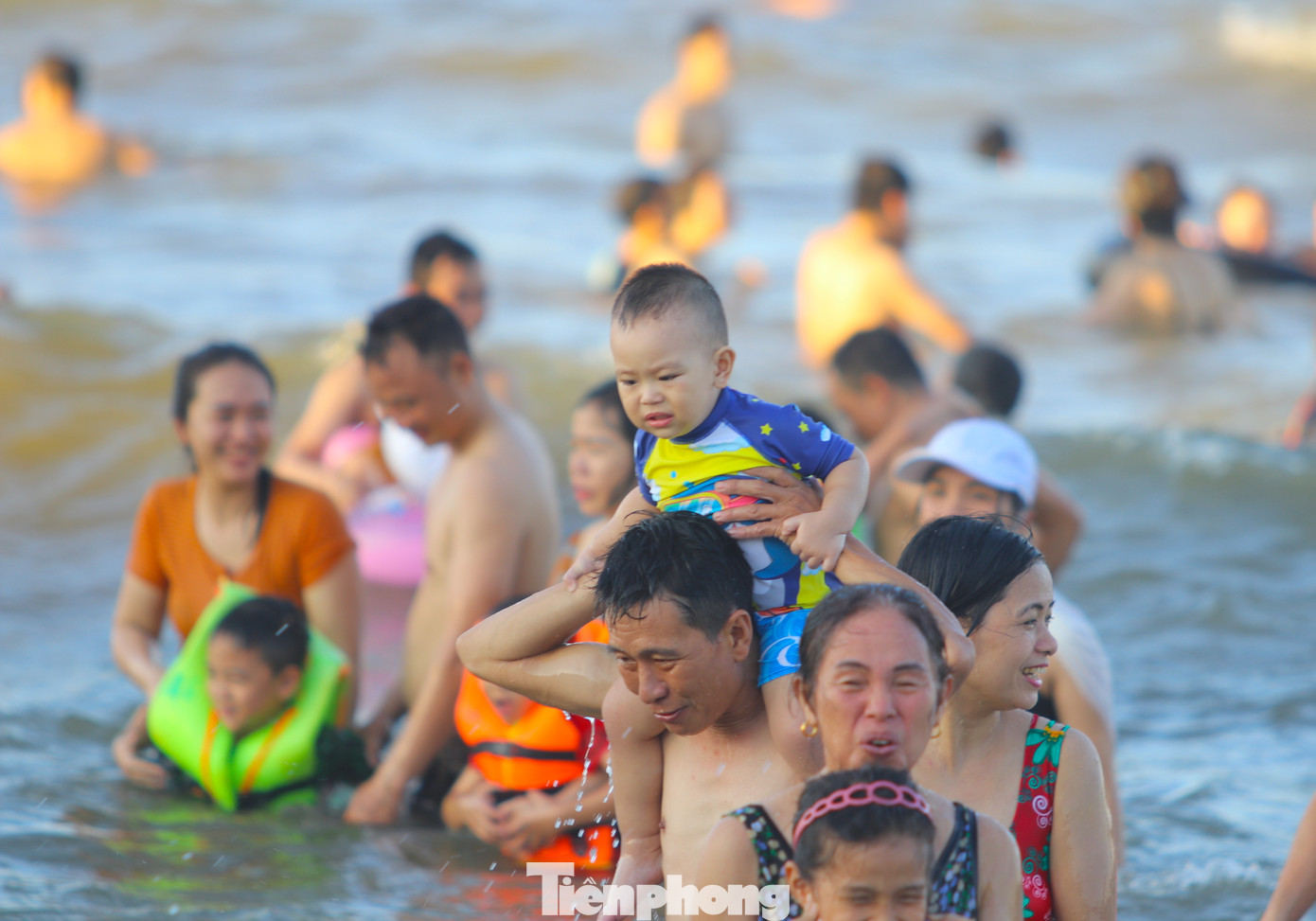 Nhiều em nhỏ dù chưa biết đi cũng được bố mẹ cõng lên vai ra chơi đùa cùng với sóng biển.