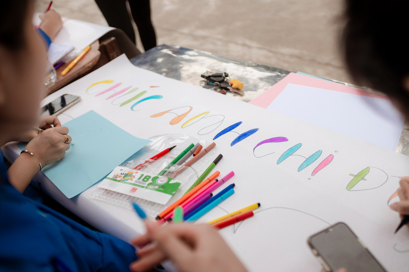 Trước cổng trường THPT Anh Sơn 3, tranh thủ chưa đến giờ thi, những nữ tình nguyện viên thể hiện tài vẽ tranh với những câu cổ động đầy màu sắc.