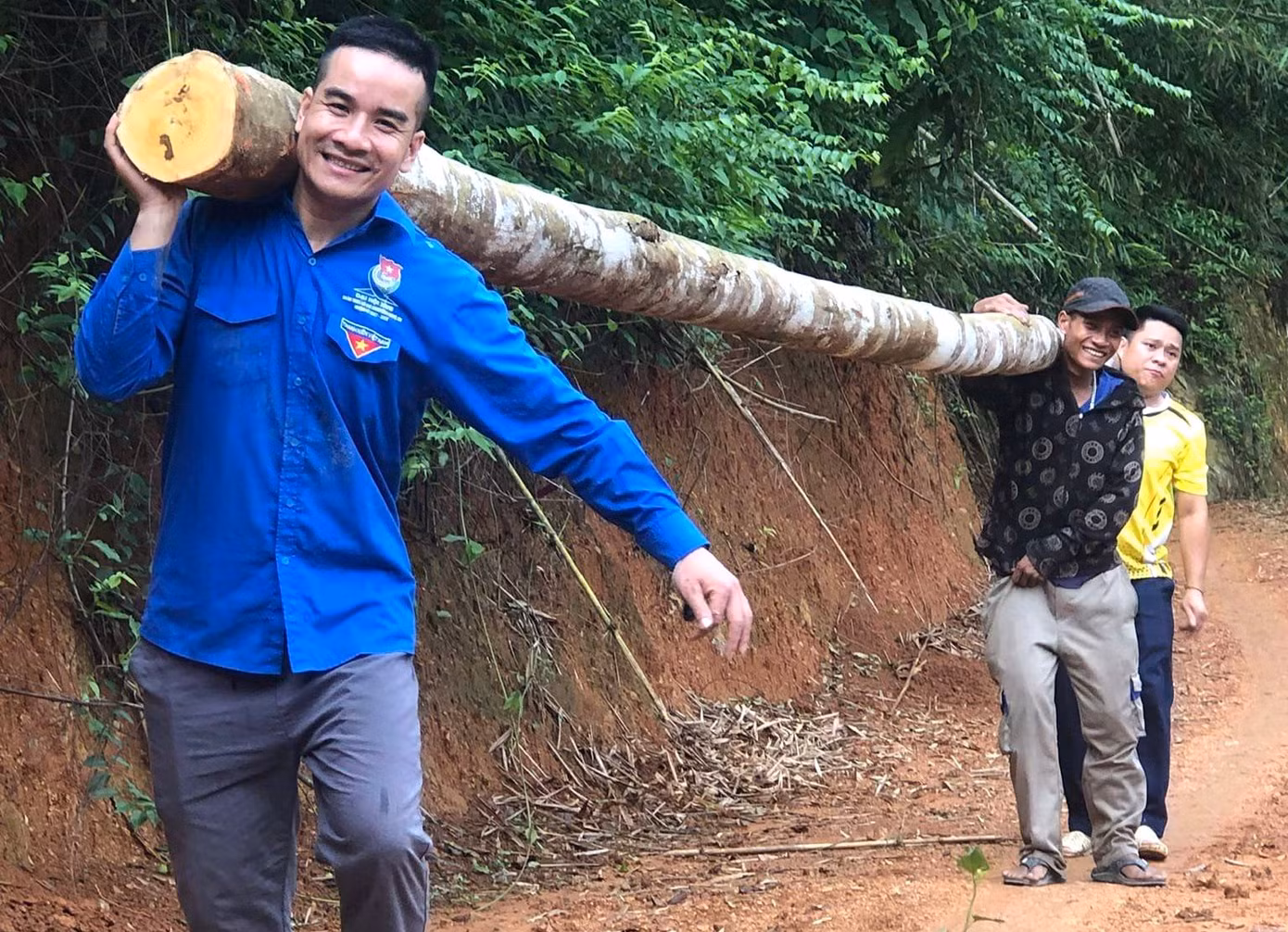 Đoàn viên thanh niên, cán bộ xã và người dân vác nhiều cây gỗ lớn để làm cầu tạm cho bà con dân bản đi.
