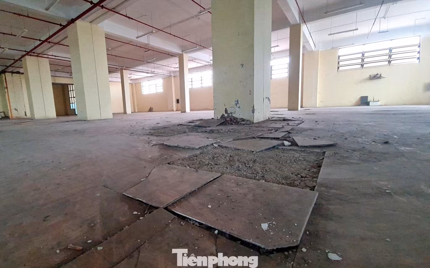 Trần nhà bị bong tróc, từng mảng sơn rơi ra ngoài. Phía dưới, nền gạch bong tróc, vỡ vụn.