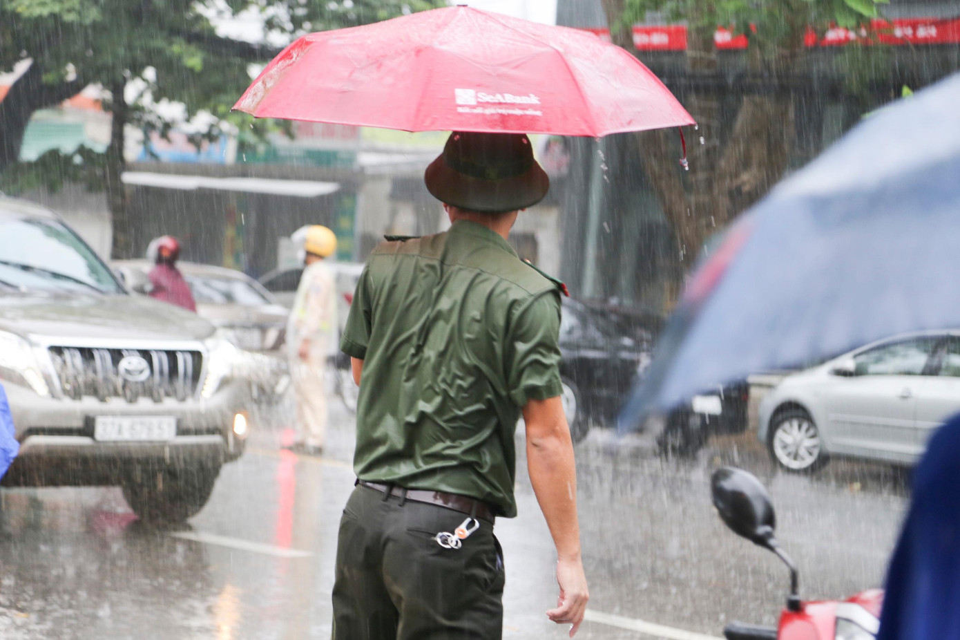 Hình ảnh đẹp người chiến sỹ công an nhân nhân ướt mưa đợi hỗ trợ thí sinh.