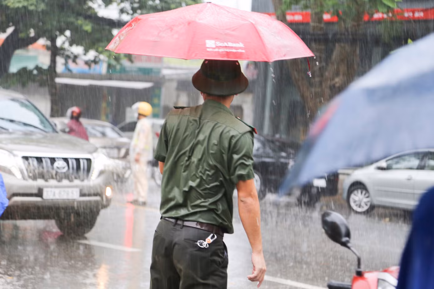 Hình ảnh đẹp người chiến sỹ công an nhân nhân ướt mưa đợi hỗ trợ thí sinh.