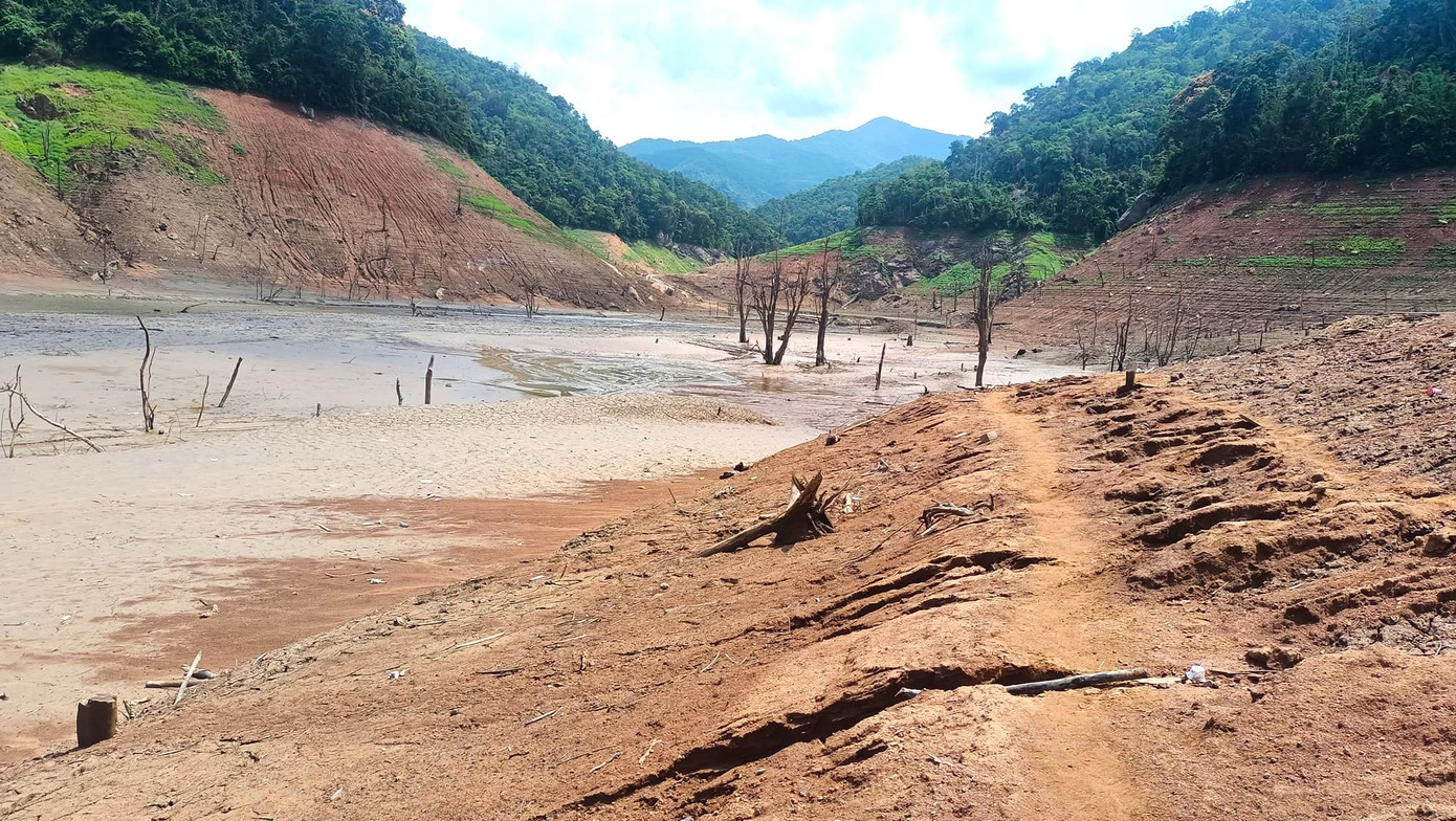 Nước trong lòng hồ rút đi lộ ra nhiều cây cối chết khô và để lại một lớp bùn đất khô.