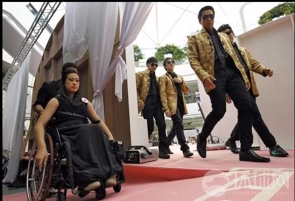 Họ được giúp đỡ khi đẩy xe lăn bước lên sân khấu 