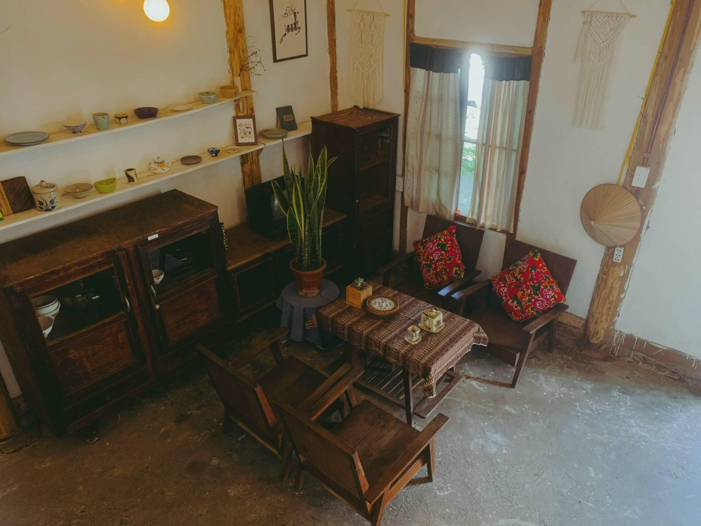 Tại phòng khách, gia chủ bày biện một bộ bàn ghế gỗ cũ kết hợp với những chiếc đệm họa tiết chăn con công của thập kỷ trước.