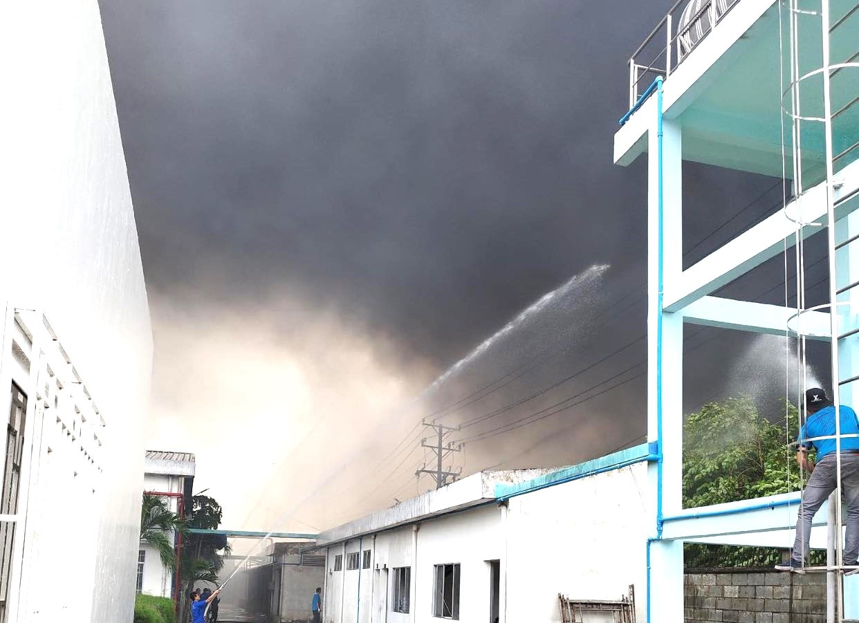Công nhân của một công ty gần hiện trường phun nước để ngăn ngọn lửa cháy lan Công nhân của một công ty gần hiện trường phun nước để ngăn ngọn lửa cháy lan
