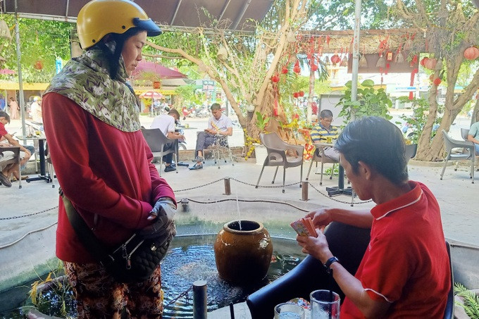 Một người đàn ông Bạc Liêu vừa nhâm nhi cà phê vừa mua vé số (Ảnh: Huỳnh Hải).