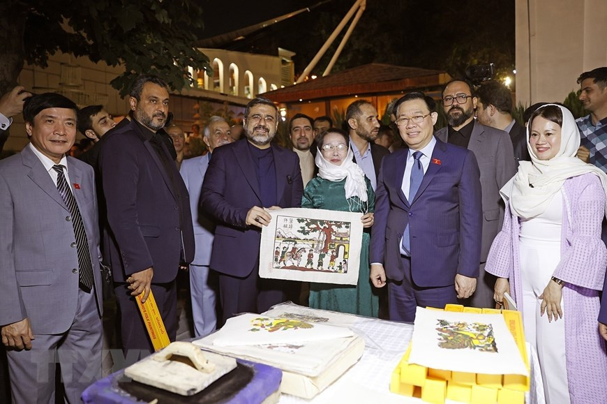 Chủ tịch Quốc hội Vương Đình Huệ và Bộ trưởng Văn hóa và Định hướng Hồi giáo Iran Mohammad Mehdi Esmaili tham quan gian trưng bày, giới thiệu sản phẩm tranh Đông Hồ. (Ảnh: Doãn Tấn/TTXVN)