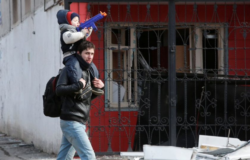 Một người đàn ông cùng con trai đi gần ngôi nhà bị hư hỏng ở Mariupol ngày 20/3. (Ảnh: Reuters) Một người đàn ông cùng con trai đi gần ngôi nhà bị hư hỏng ở Mariupol ngày 20/3. (Ảnh: Reuters)