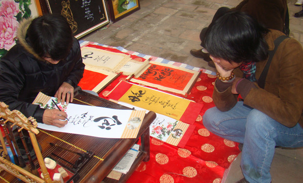 ... một chàng trai say mê ngắm ông đồ trẻ viết chữ Tài.