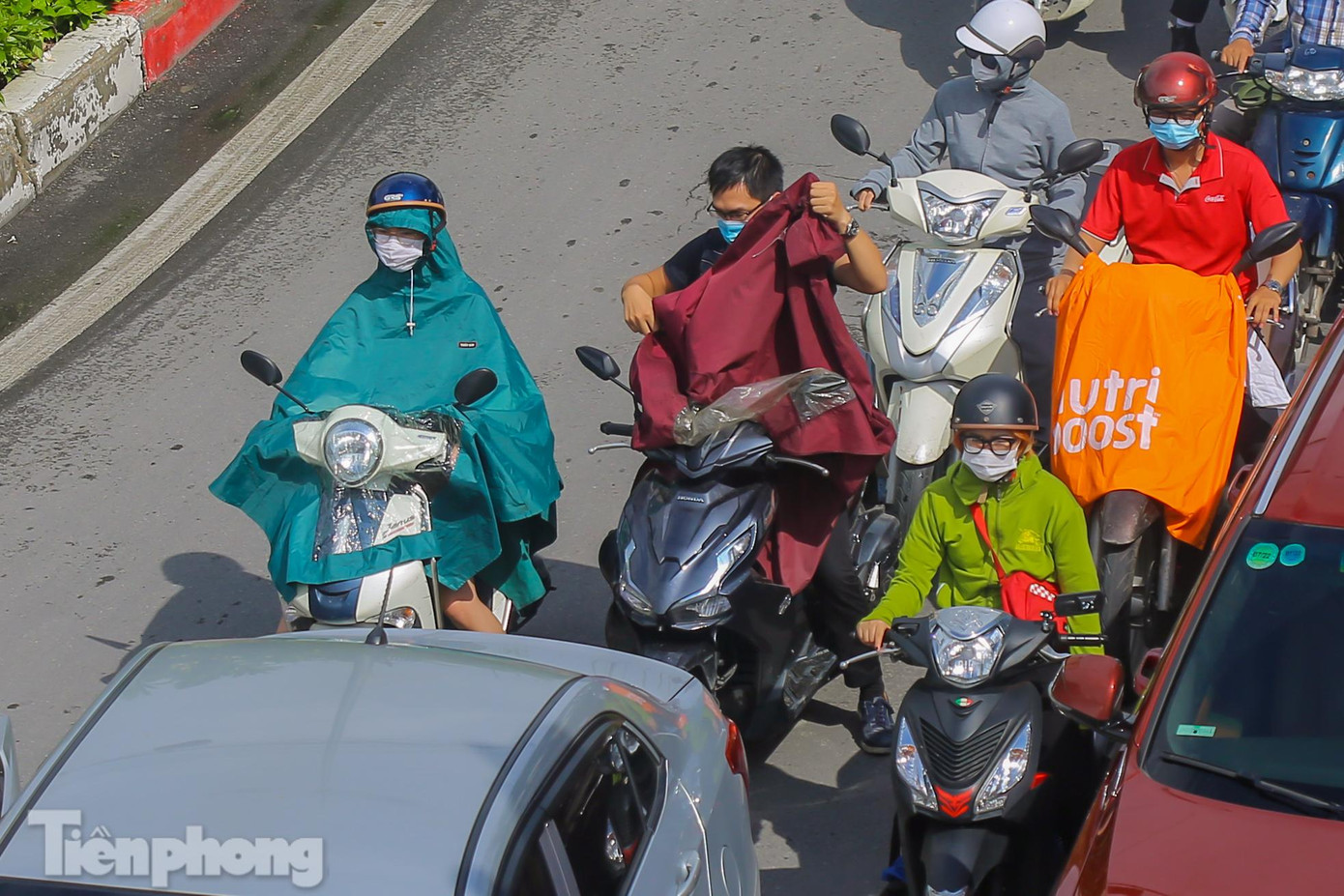 Người dân tranh thủ cởi áo mưa khi trời bất chợt lại nắng to.