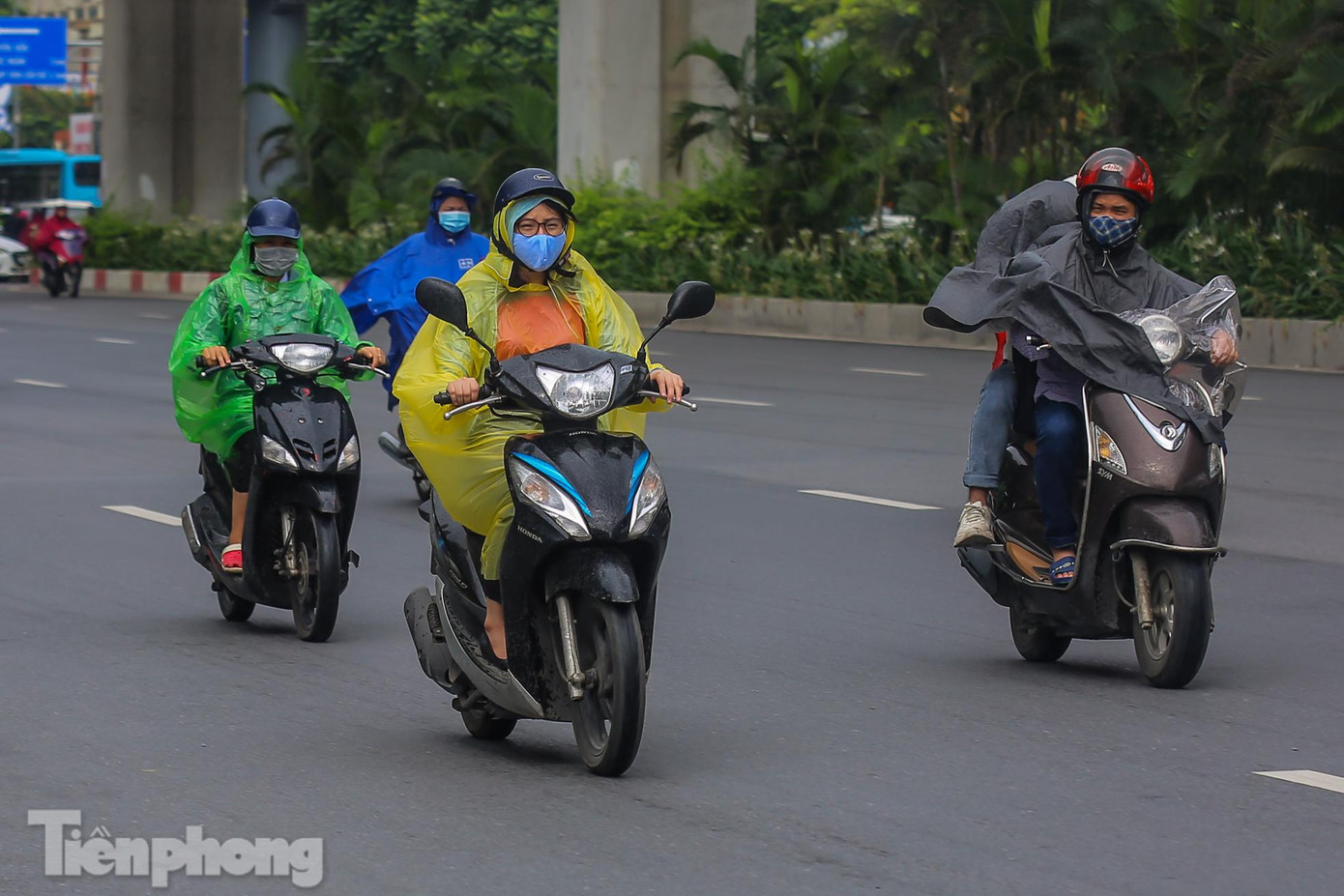 Nắng mưa thất thường, nhiều người mặc áo mưa đi làm.