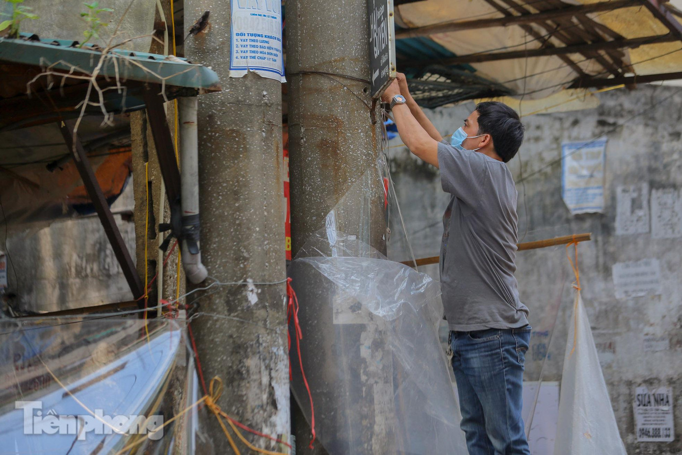Người đàn ông gia cố thêm lớp ni lông cho gian hàng.