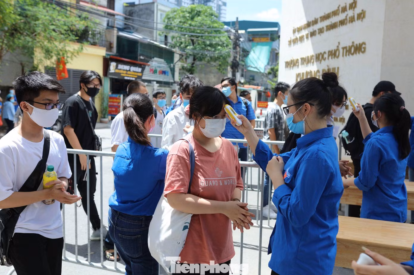 Tại điểm thi trường THPT Khương Đình, các tình nguyện viên đo thân nhiệt, rửa tay sát khuẩn cho các thí sinh trước khi vào trường.