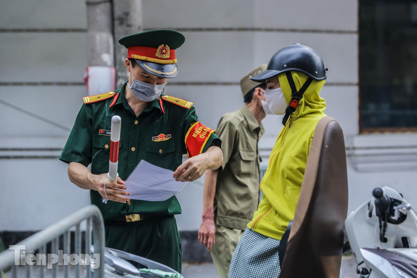 Lực lượng quân đội tham gia việc kiểm tra giấy tờ tùy thân và xác nhận đi làm, ra ngoài của cơ quan với người dân lưu thông trên đường.