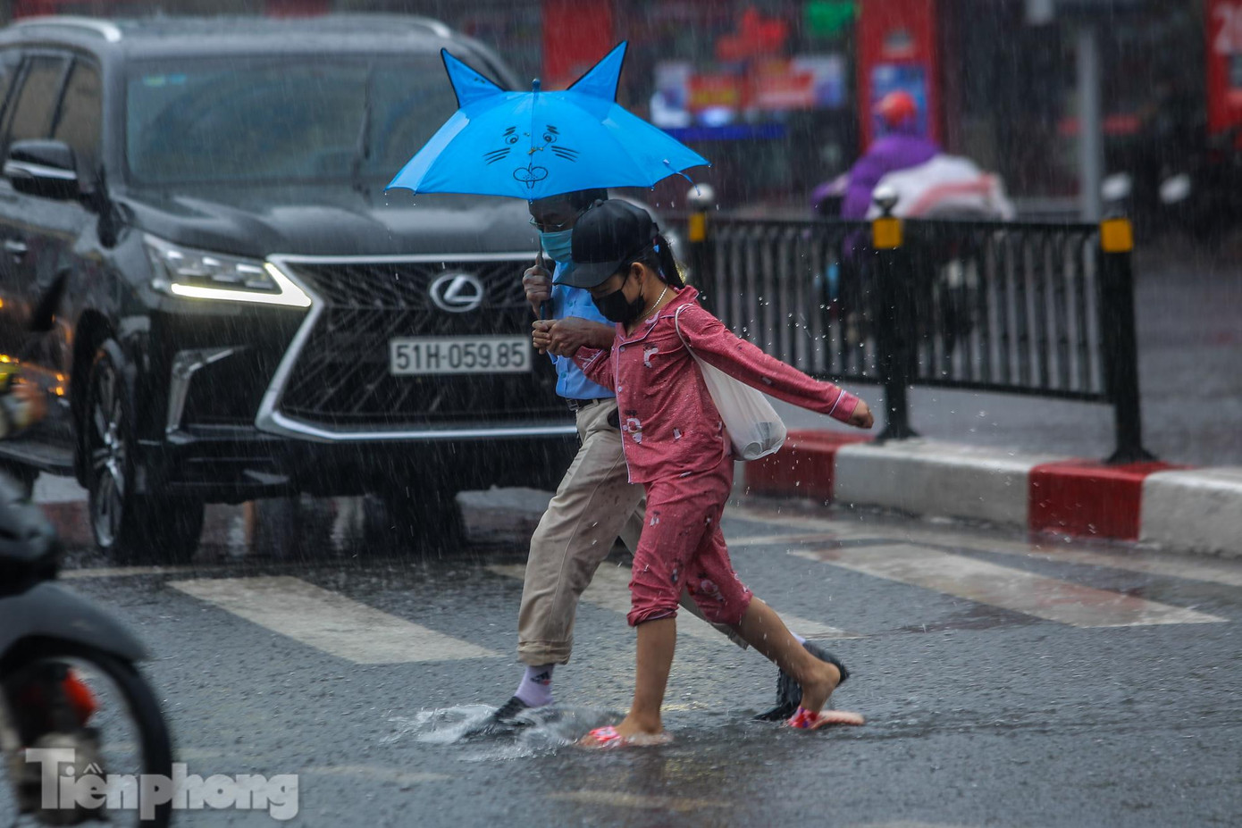 Người đi bộ vất vả băng qua đường trong cơn mưa lớn.