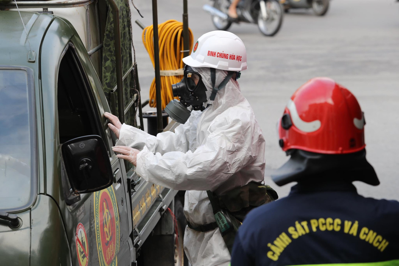 Những chiến sĩ trực tiếp phun khử khuẩn được trang bị mặt nạ phòng độc. Ảnh: Hoàng Mạnh Thắng.