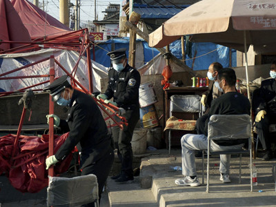 Ngày 13/4, các nhân viên bảo vệ dọn sạch quầy hàng gia cầm của bố mẹ bệnh nhi 7 tuổi nhiễm H7N9. Quầy hàng ở bên ngoài gia đình họ ở làng Gucheng, huyện Shunyia, ngoại thành Bắc Kinh. Ảnh: AP