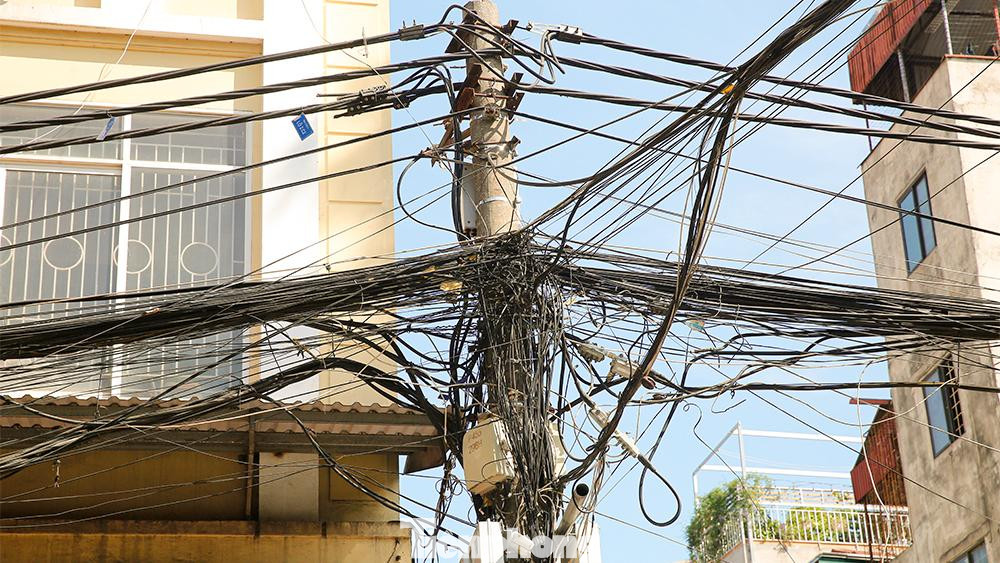 Dọc tuyến phố Đê La Thành, dây viễn thông và đường dây điện trung 'rối như tơ nhện'. Dọc tuyến phố Đê La Thành, dây viễn thông và đường dây điện trung 'rối như tơ nhện'.