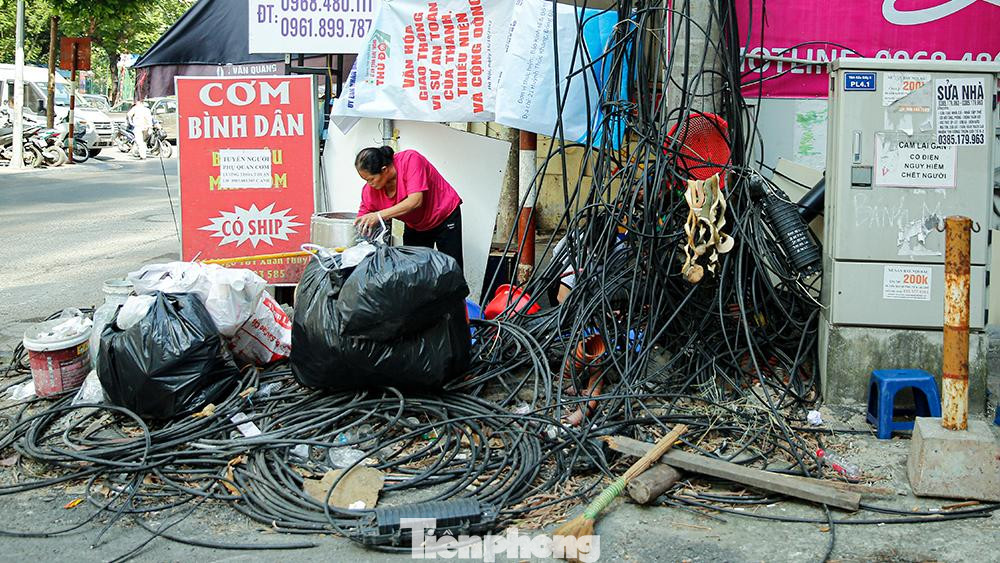 Dây điện, cáp viễn thông xen lẫn nơi tập kết rác của người dân. Dây điện, cáp viễn thông xen lẫn nơi tập kết rác của người dân.