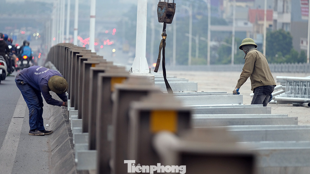 Công nhân đang lắp đặt lan can phía bờ Đông với phần mặt cầu đã được cơ bản hoàn thiện.