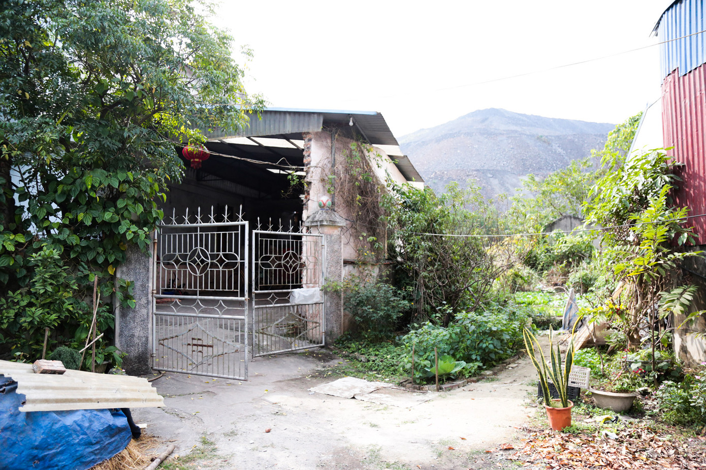 Chưa được có đất để tái định cư, gia đình bà Lê Thị Dung vẫn phải ở lại trong ngôi nhà gần bãi thải đất đá. Ảnh: Hân Nguyễn.