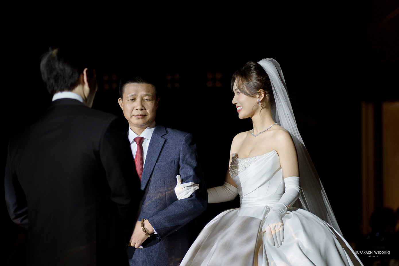 Ngọc Anh được bố dẫn vào lễ đường trong tiệc cưới. Sau đó, cặp đôi cùng thực hiện các nghi thức truyền thống như trao nhẫn, uống rượu giao bôi, thề nguyện... Ảnh: Nupakachi Wedding.