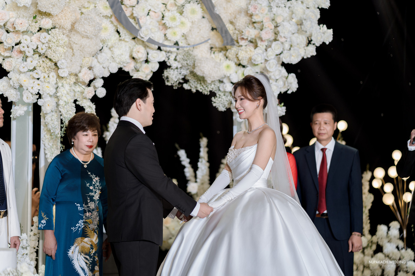 Ngọc Anh được bố dẫn vào lễ đường trong tiệc cưới. Sau đó, cặp đôi cùng thực hiện các nghi thức truyền thống như trao nhẫn, uống rượu giao bôi, thề nguyện... Ảnh: Nupakachi Wedding.