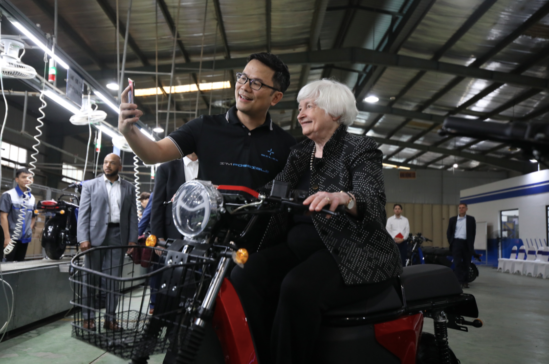 Bộ trưởng Tài chính Mỹ Janet Yellen ngồi thử chiếc xe máy điện do một doanh nghiệp khởi nghiệp của Việt Nam sản xuất. (Ảnh: TĐ)