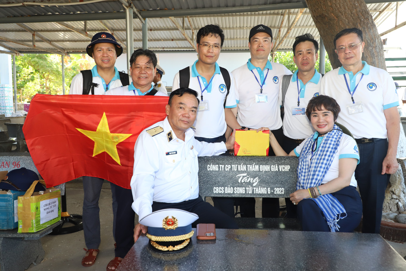 Chuẩn Đô đốc Phạm Văn Quang - Phó Chủ nhiệm Chính trị Quân chủng Hải quân cùng các thành viên đoàn công tác chụp ảnh lưu niệm bên quốc kỳ có con dấu và chữ ký của chỉ huy các điểm đảo mà đoàn đến thăm.