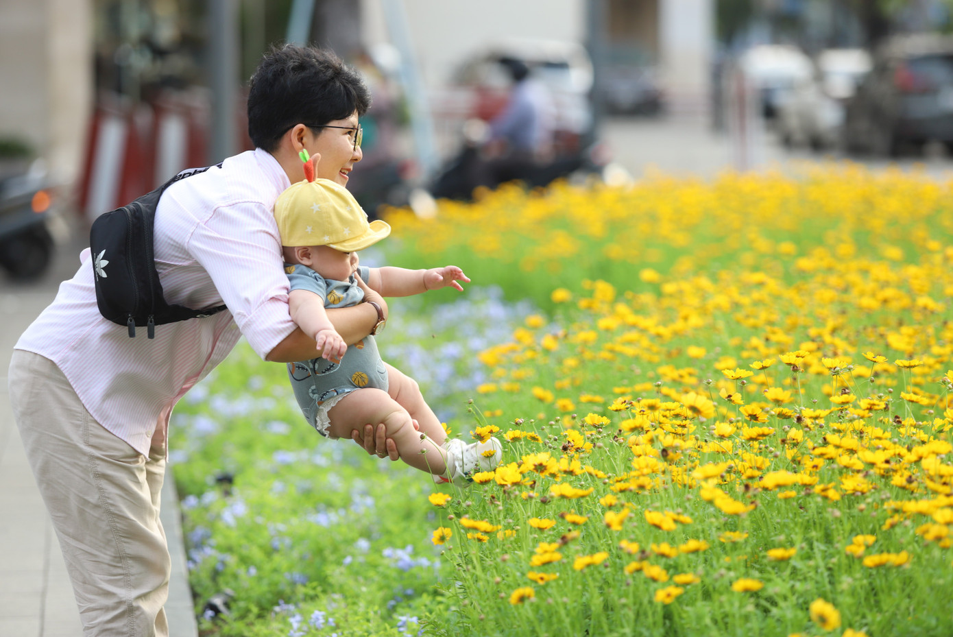 Em bé được người thân cho nô đùa cùng tràng hoa vàng ươm.