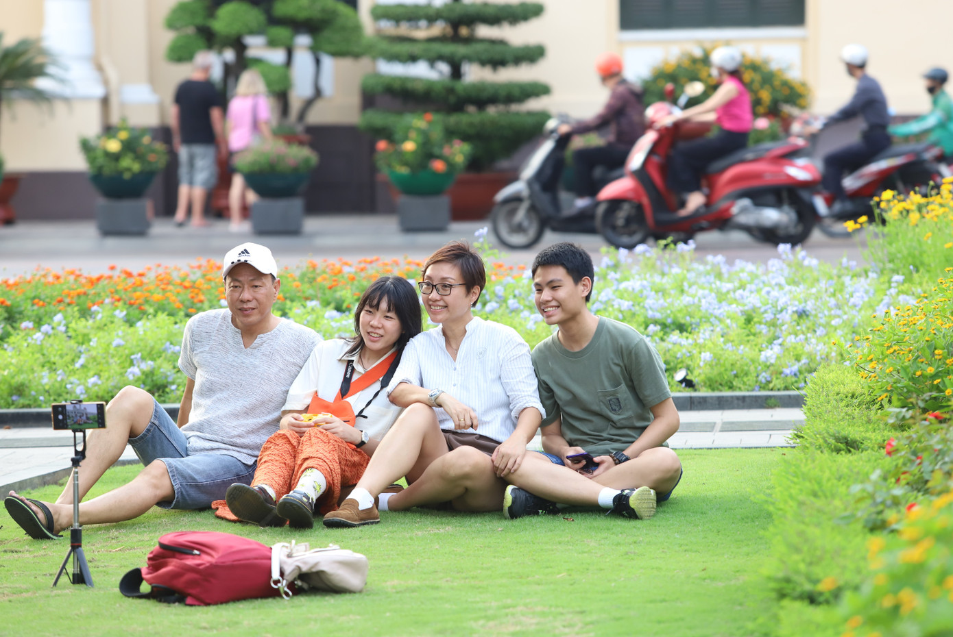 Một gia đình du khách chụp hình lưu niệm với không gian vườn hoa phía trước UBND TPHCM.
