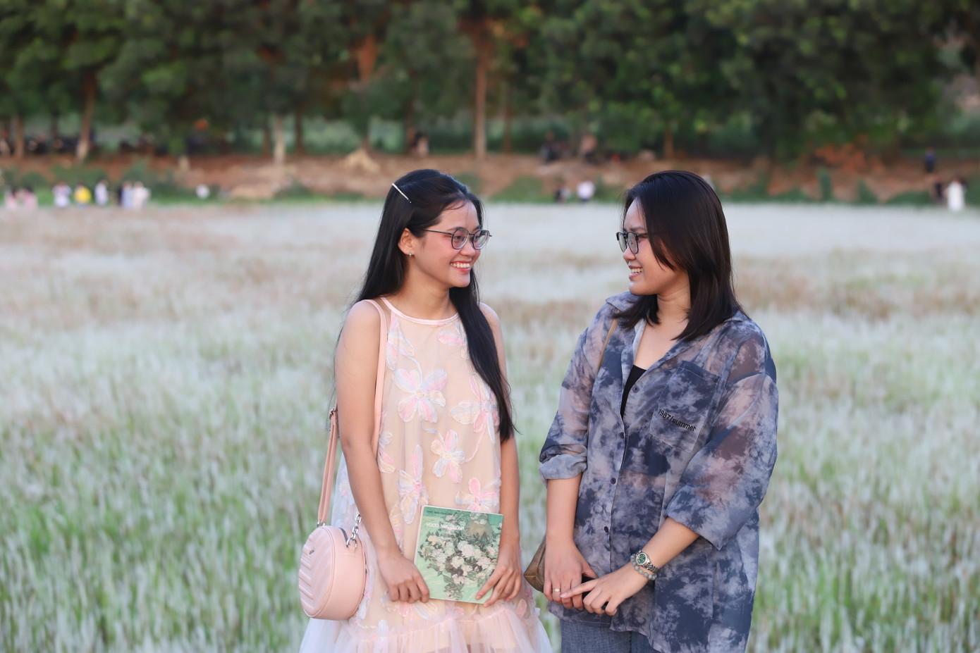 Chiều cuối tuần, Thúy Ngọc (phải, sinh viên khoa Y, Đại học Quốc gia TPHCM) và Hồng Hoa (sinh viên Trường Đại học Bách khoa, Đại học Quốc gia TPHCM) "lên đồ" để đi chụp ảnh sau khi có thông tin về đồng cỏ lau được các bạn chia sẻ trên trang cộng đồng ký túc xá. "Nhìn khung cảnh nơi đây rất yên bình và chill", Ngọc nói về đồng cỏ và cho biết lúc trước cũng từng chụp ảnh ở những cánh đồng cỏ lau rộng lớn ở quê nhà Tiền Giang.